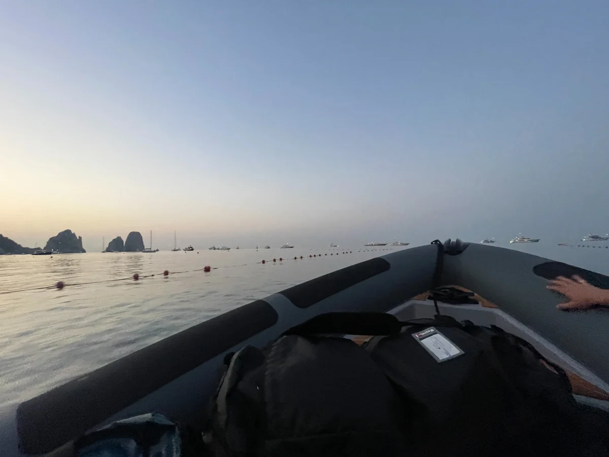 View from an inflatable boat approaching a rocky coastline at dusk